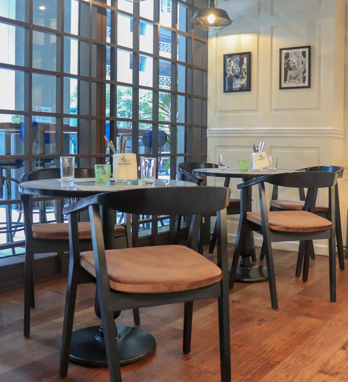 Black dining chairs with warm brown seat cushions around round restaurant tables.