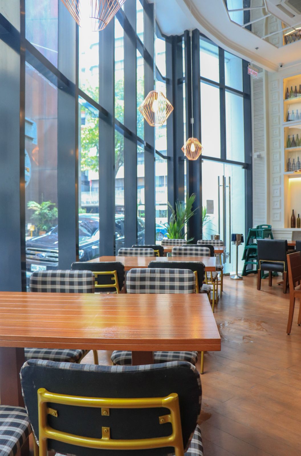 Plaid upholstered dining chairs and wood tables in a light-filled restaurant space.