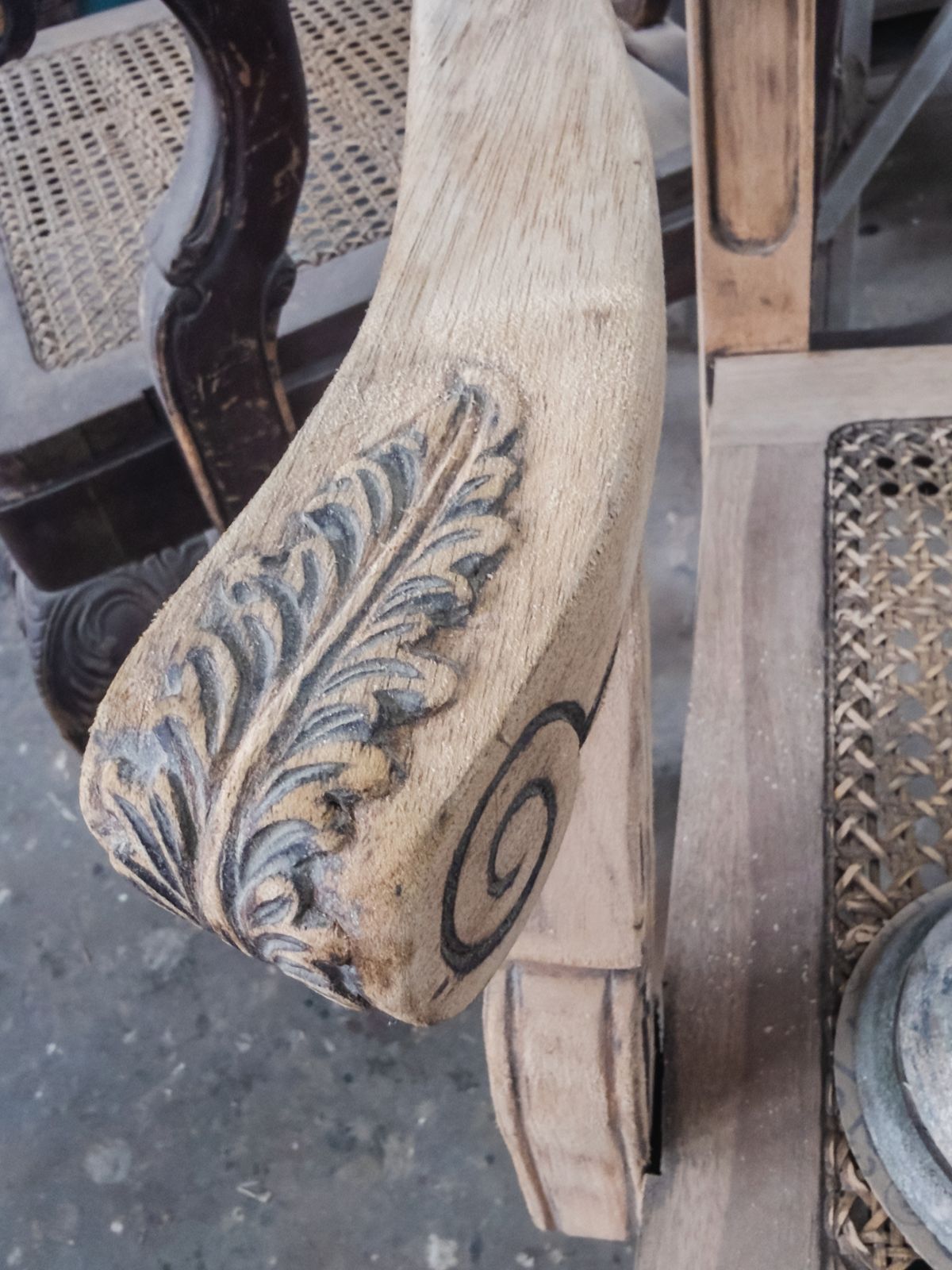 Close-up of a carved wooden chair arm during careful surface preparation.