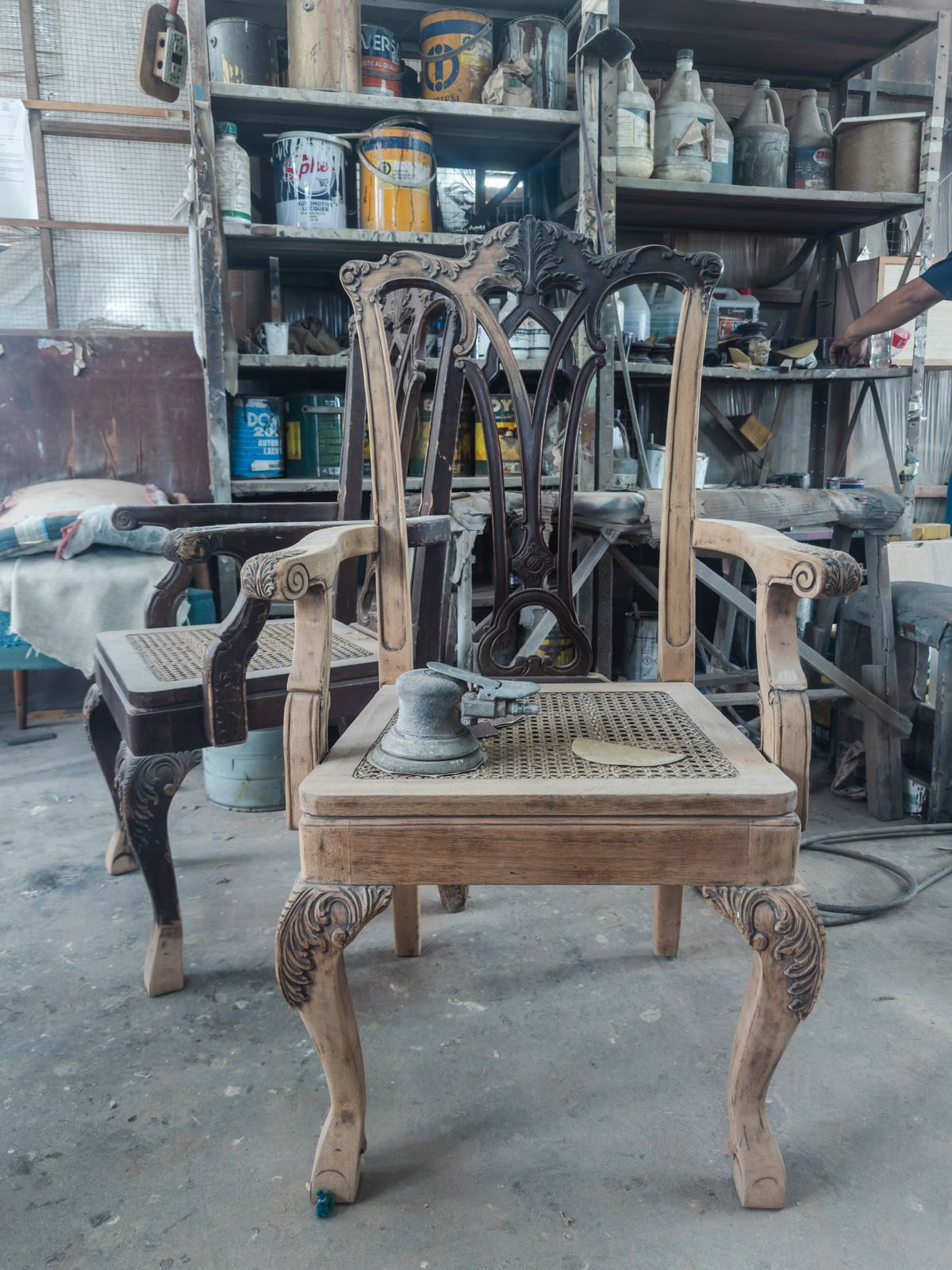 Carved wooden chair with areas of aged finish removed during workshop preparation.