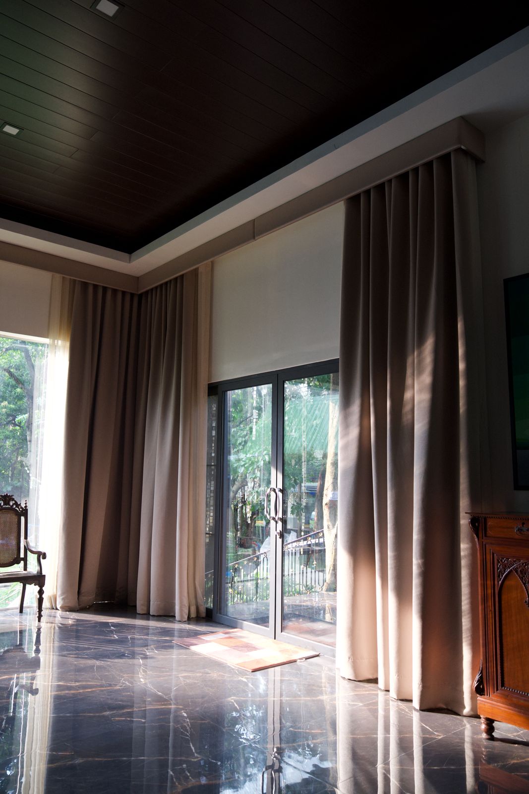 Neutral floor-to-ceiling drapery panels framing corner windows and sliding glass doors.